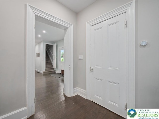 hallway featuring dark wood-style flooring, baseboards, and stairs
