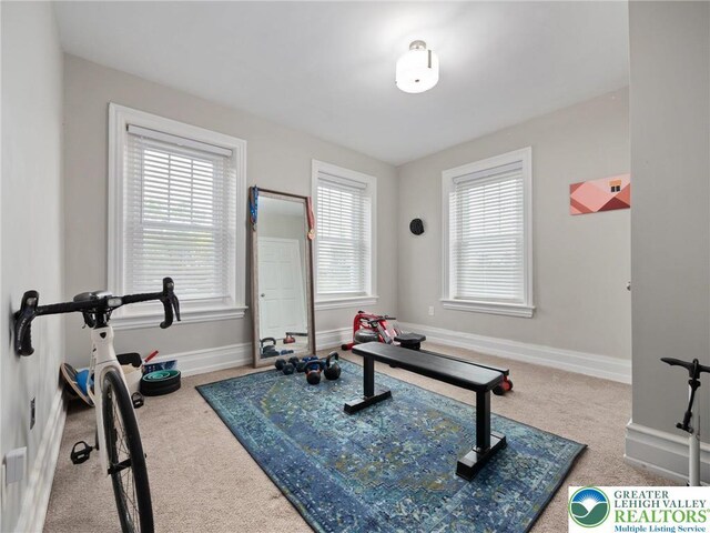 workout room featuring carpet flooring, plenty of natural light, and baseboards