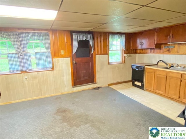 kitchen featuring wooden walls, a drop ceiling, and light carpet