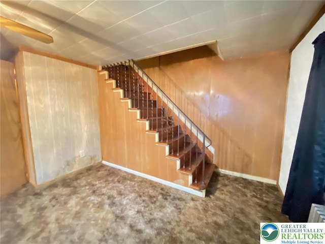 stairs featuring wood walls and carpet floors
