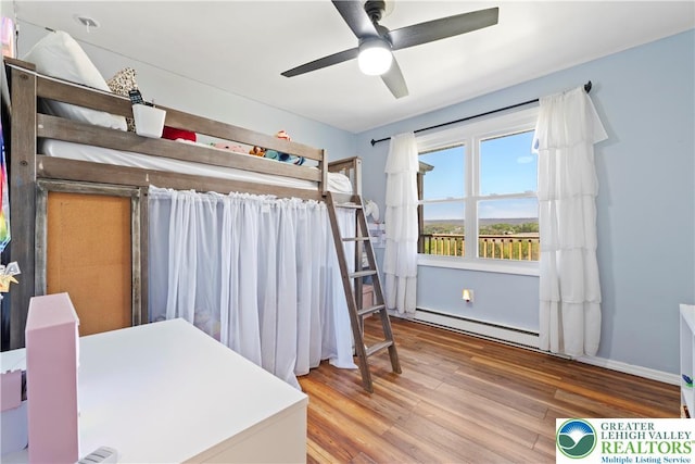 bedroom featuring baseboard heating, wood finished floors, and a ceiling fan