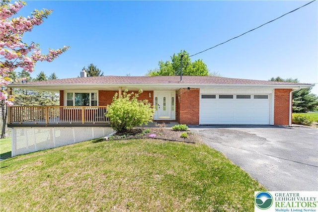 ranch-style house with driveway, an attached garage, a front yard, brick siding, and a chimney