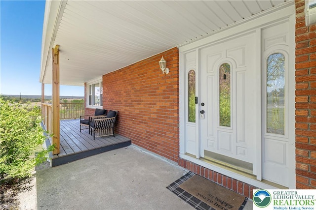 entrance to property featuring a porch and brick siding