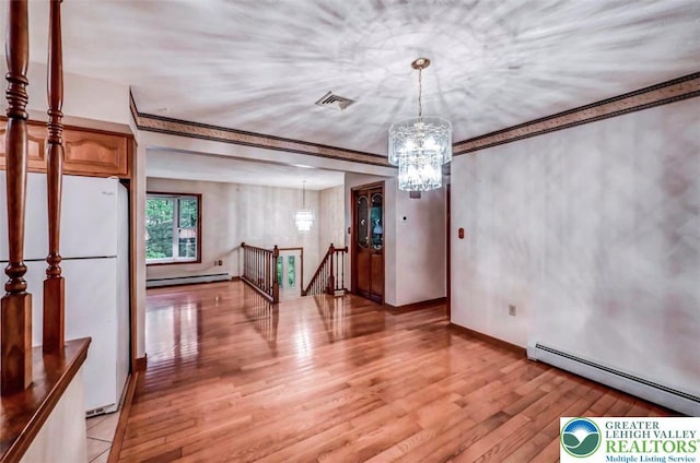 unfurnished dining area featuring a baseboard heating unit, light wood-style floors, baseboard heating, and a chandelier