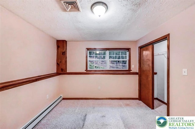 spare room featuring a baseboard radiator, a textured ceiling, carpet, and baseboards
