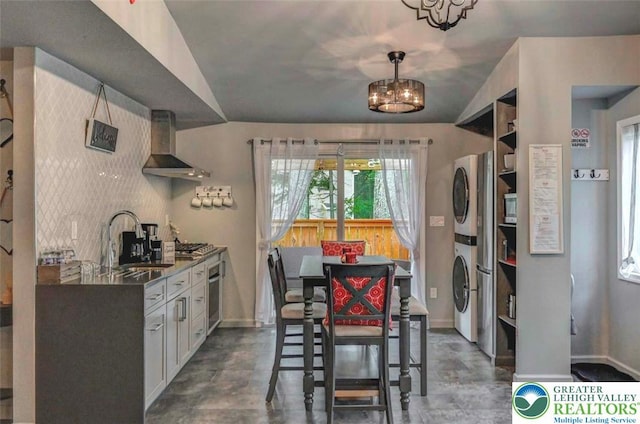 304 Ruger Ln, Coolbaugh Twp, PA 18466 - kitchen featuring wall chimney range hood, stacked washer / drying machine, oven, a sink, and baseboards