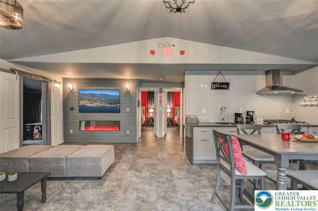 304 Ruger Ln, Coolbaugh Twp, PA 18466 - kitchen with wall chimney exhaust hood, lofted ceiling, a large fireplace, a sink, and a barn door