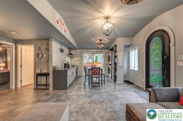 304 Ruger Ln, Coolbaugh Twp, PA 18466 - dining space with estacked washer and dryer, baseboards, arched walkways, a chandelier, and vaulted ceiling