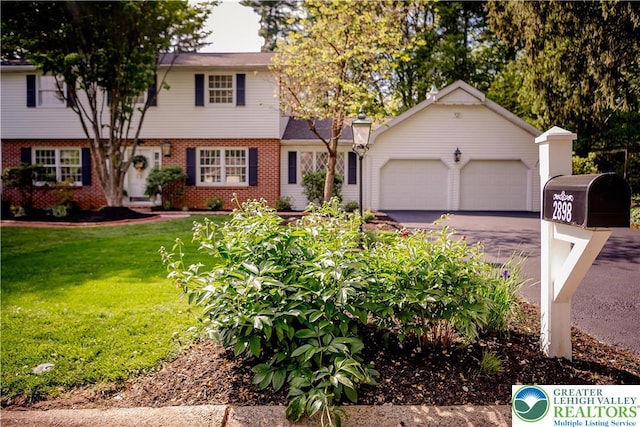colonial-style house with asphalt driveway, a garage, brick siding, and a front lawn