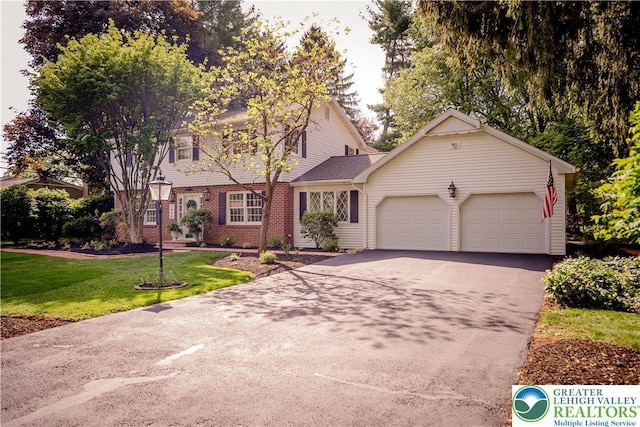 view of front facade with a garage, asphalt driveway, a front yard, and brick siding