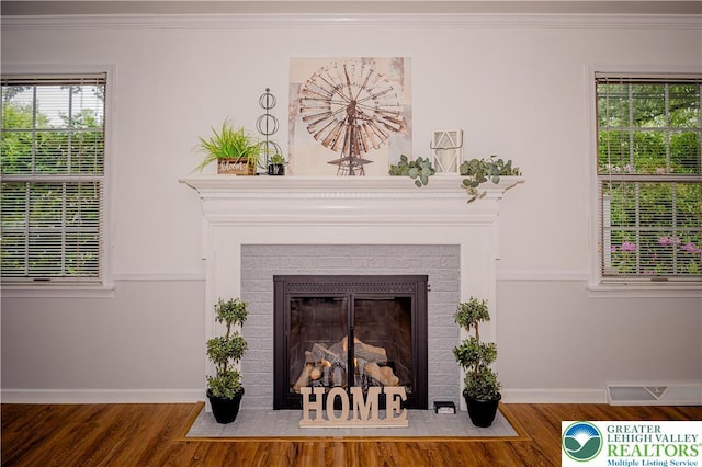 detailed view of baseboards, wood finished floors, a fireplace, and ornamental molding