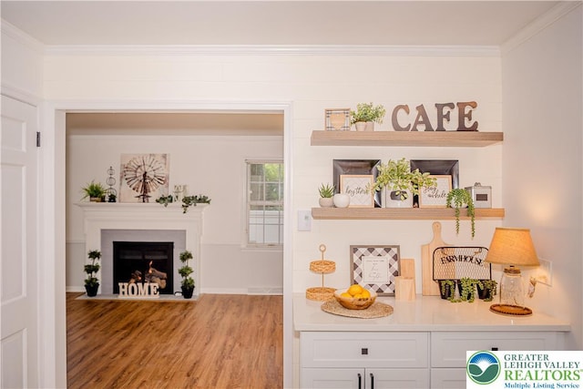 detailed view of wood finished floors, a fireplace with flush hearth, and crown molding