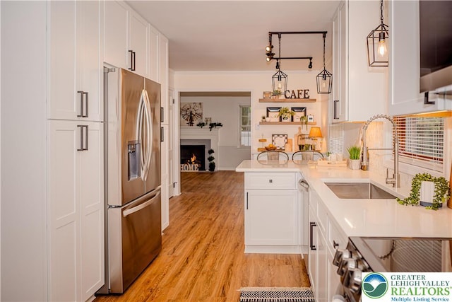 kitchen with stainless steel fridge with ice dispenser, a sink, white cabinetry, gas range oven, and light wood-style floors