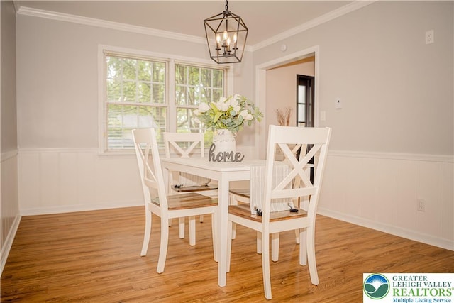 dining area with a chandelier, wainscoting, wood finished floors, and ornamental molding
