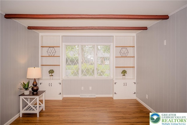 spare room featuring beam ceiling, wood finished floors, wood walls, and baseboards
