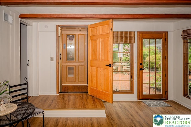 doorway with wood finished floors, beam ceiling, and baseboards