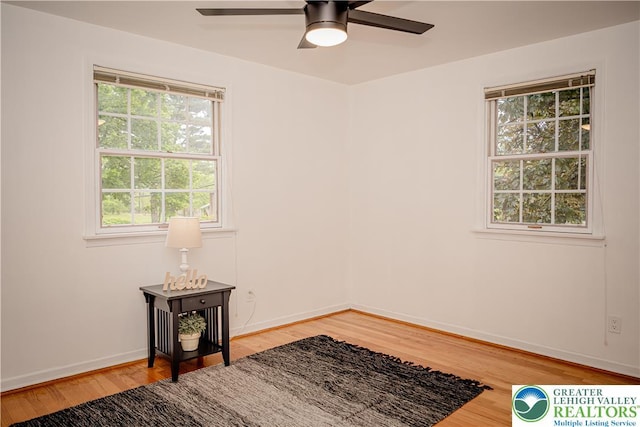 spare room with ceiling fan, light wood-style floors, and baseboards