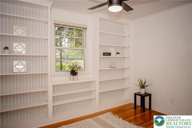detailed view of wood finished floors, ornamental molding, a ceiling fan, built in features, and baseboards