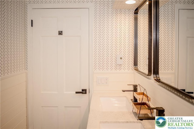 bathroom featuring wallpapered walls and a sink