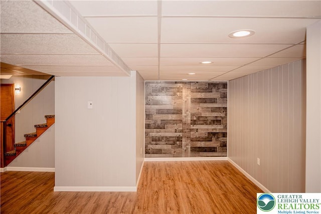 spare room featuring baseboards, wood finished floors, stairway, wood walls, and recessed lighting