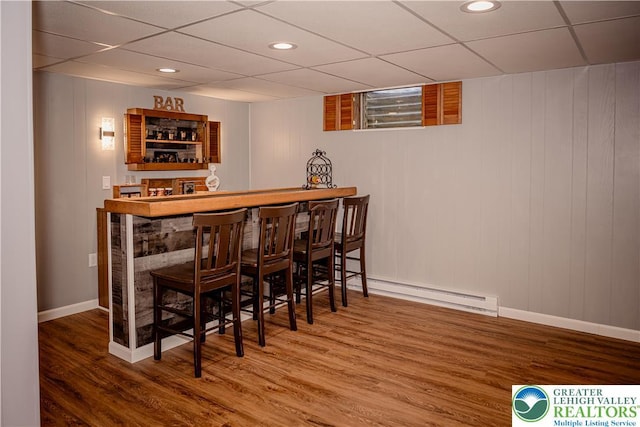 indoor dry bar with baseboard heating, wood finished floors, a drop ceiling, baseboards, and recessed lighting