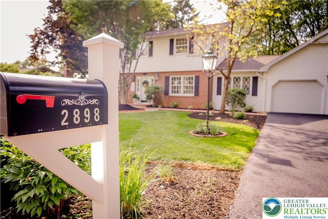 view of front of home with an attached garage, brick siding, a front yard, and asphalt driveway