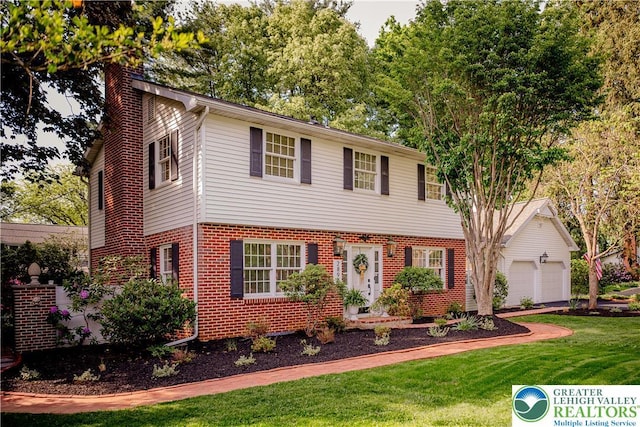 view of front of home featuring brick siding, a chimney, a front lawn, and a garage