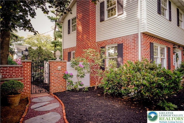view of side of property featuring a gate and brick siding