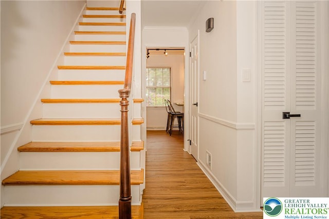 stairway featuring wood finished floors and crown molding