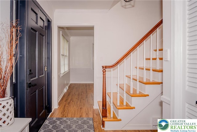 entrance foyer with stairs, crown molding, and light wood finished floors