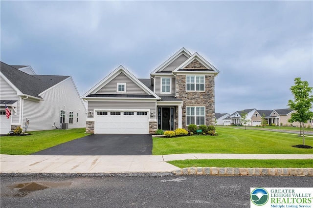 craftsman-style house with stone siding, asphalt driveway, a front yard, and central air condition unit