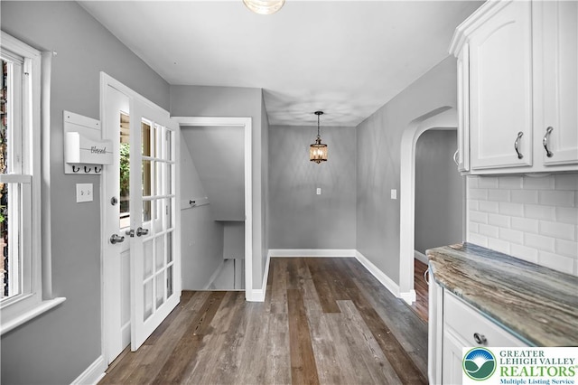entryway featuring arched walkways, dark wood-style flooring, and baseboards