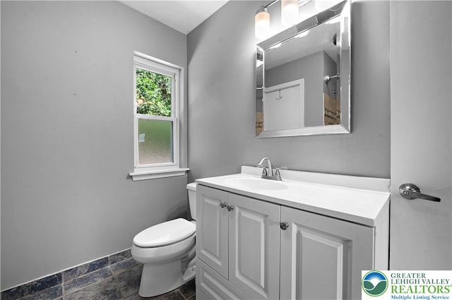 bathroom featuring vanity, toilet, and stone finish flooring