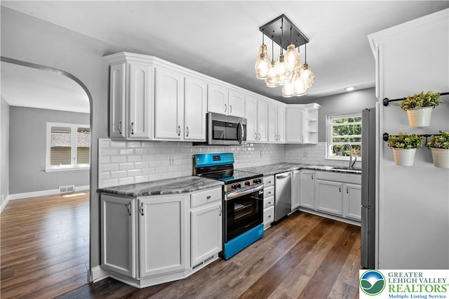 kitchen featuring appliances with stainless steel finishes, dark stone counters, open shelves, and dark wood finished floors