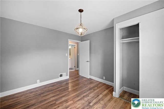 unfurnished bedroom featuring baseboards, wood finished floors, and a closet