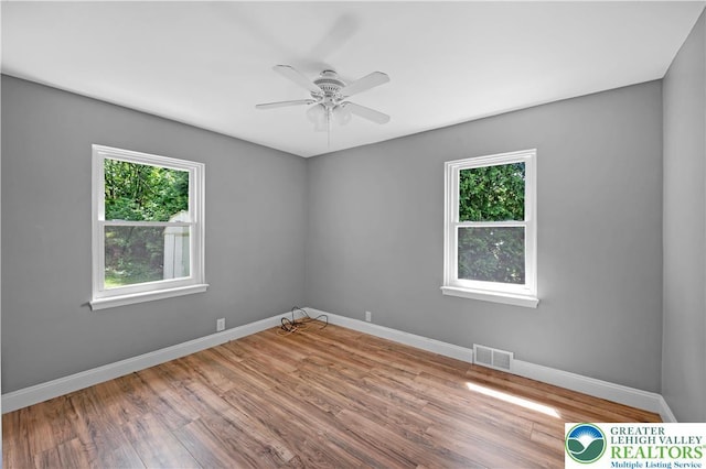 empty room featuring plenty of natural light, wood finished floors, and baseboards
