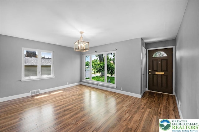 foyer entrance featuring baseboards, wood finished floors, and a chandelier