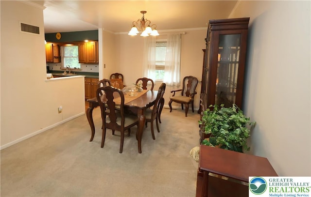 dining area with a chandelier, plenty of natural light, crown molding, baseboards, and light colored carpet