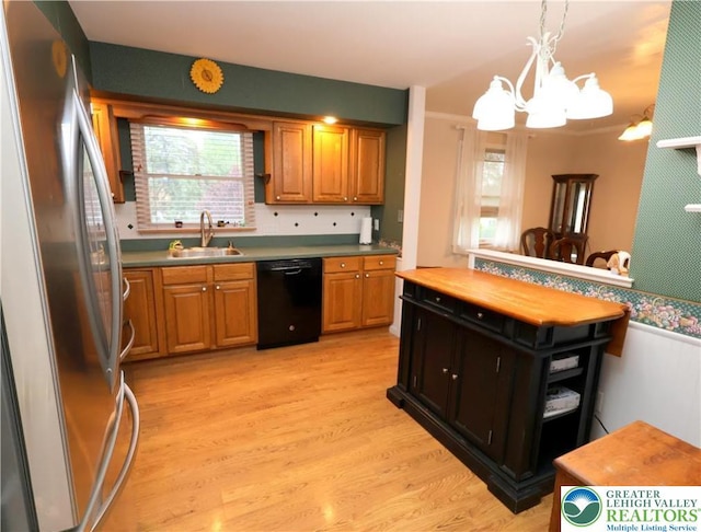 kitchen with black dishwasher, freestanding refrigerator, a sink, a chandelier, and light wood-style flooring
