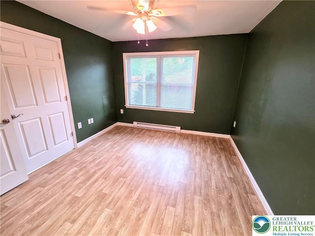 spare room featuring baseboard heating, a ceiling fan, light wood-style flooring, and baseboards