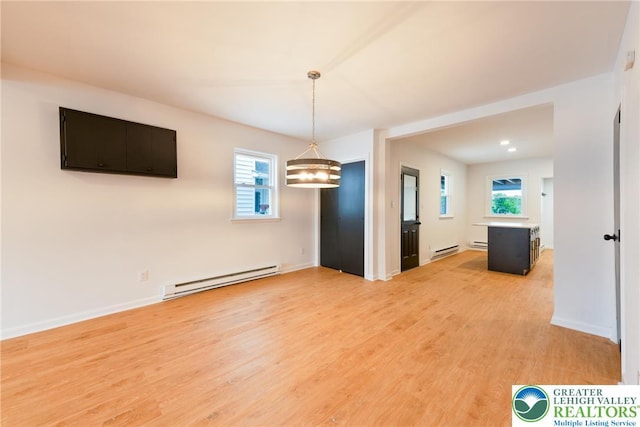 unfurnished room featuring a baseboard heating unit, light wood-style floors, and a chandelier