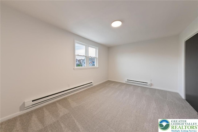 spare room with a baseboard heating unit, carpet flooring, and baseboards