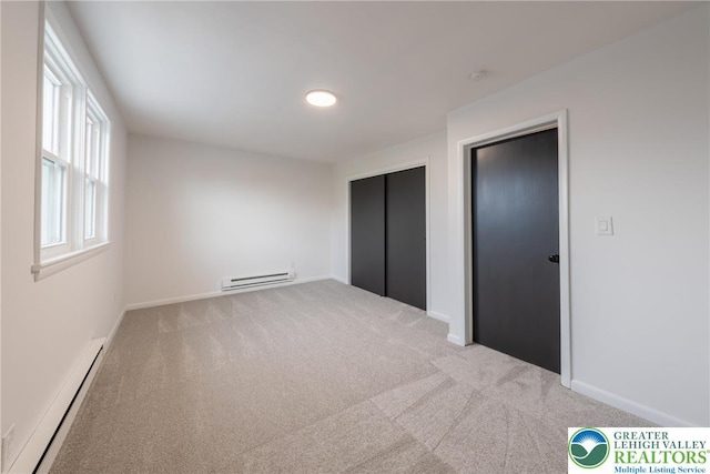 unfurnished bedroom featuring baseboard heating, a baseboard radiator, carpet, and baseboards