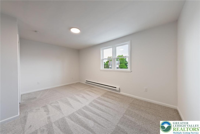 carpeted spare room featuring a baseboard heating unit and baseboards