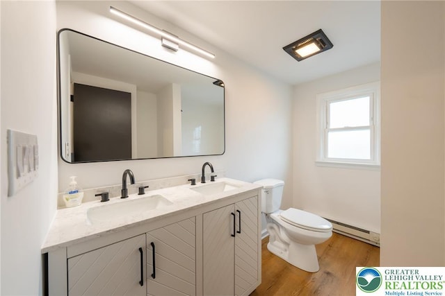 bathroom with baseboard heating, wood finished floors, toilet, and double vanity