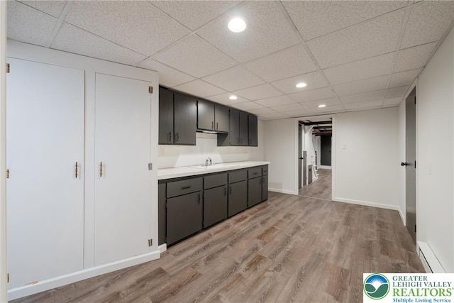 kitchen with light wood-style flooring, light countertops, a sink, a paneled ceiling, and recessed lighting
