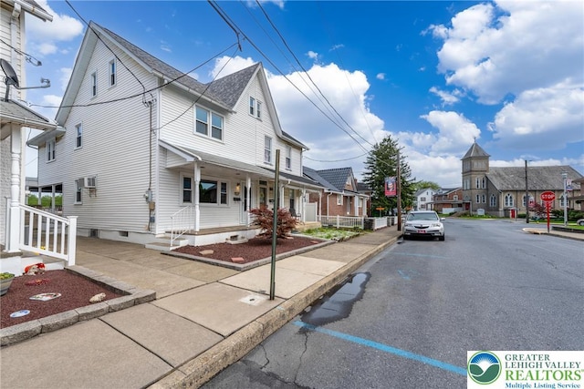 view of asphalt road featuring a residential view, sidewalks, curbs, and traffic signs