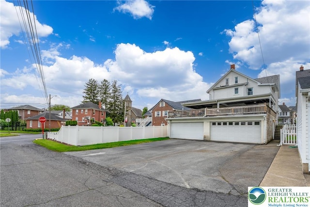 view of front of property with a residential view, fence, asphalt driveway, and an attached garage