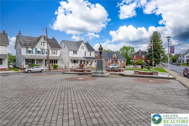 view of decorative road featuring a residential view, sidewalks, curbs, street lights, and traffic signs