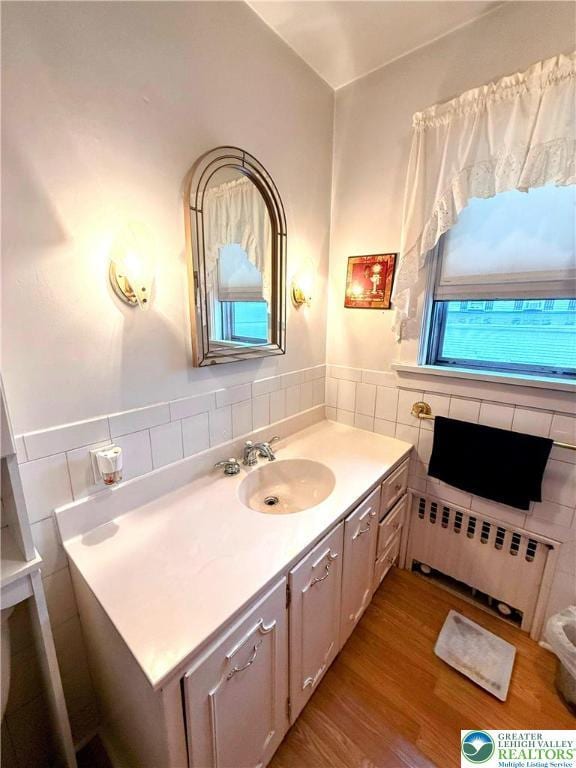 213 Main St, Pen Argyl Borough, PA 18072 - bathroom with radiator, tile walls, wood finished floors, vanity, and wainscoting